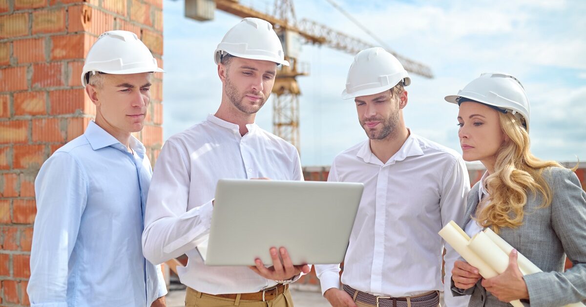 Woman and men looking at laptop at construction